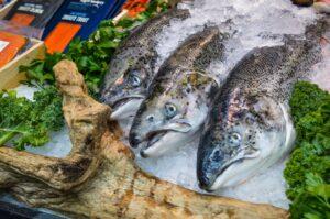 fresh fish covered with ice near vegetables